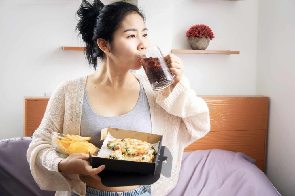 (Ilustrasi sedang konsumsi junk food yang dapat memicu terjadinya asam lambung, sumber : canva)
